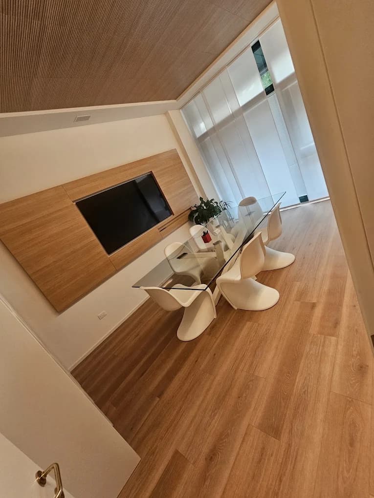 Sala riunioni pulita con tavolo in vetro e sedie bianche